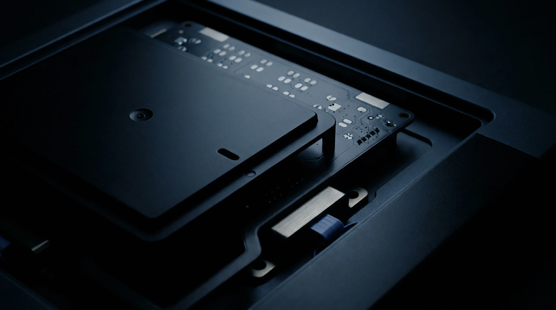 Matte black internal framing in a digital render houses a printed circuit board assembly partially covered by a rectangular radio frequency interference shield.